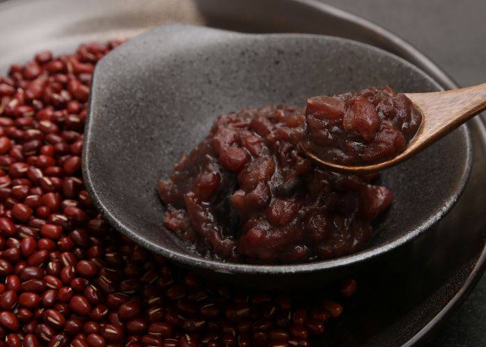 A bowl of Japanese red bean paste above a bigger bowl of uncooked red beans.